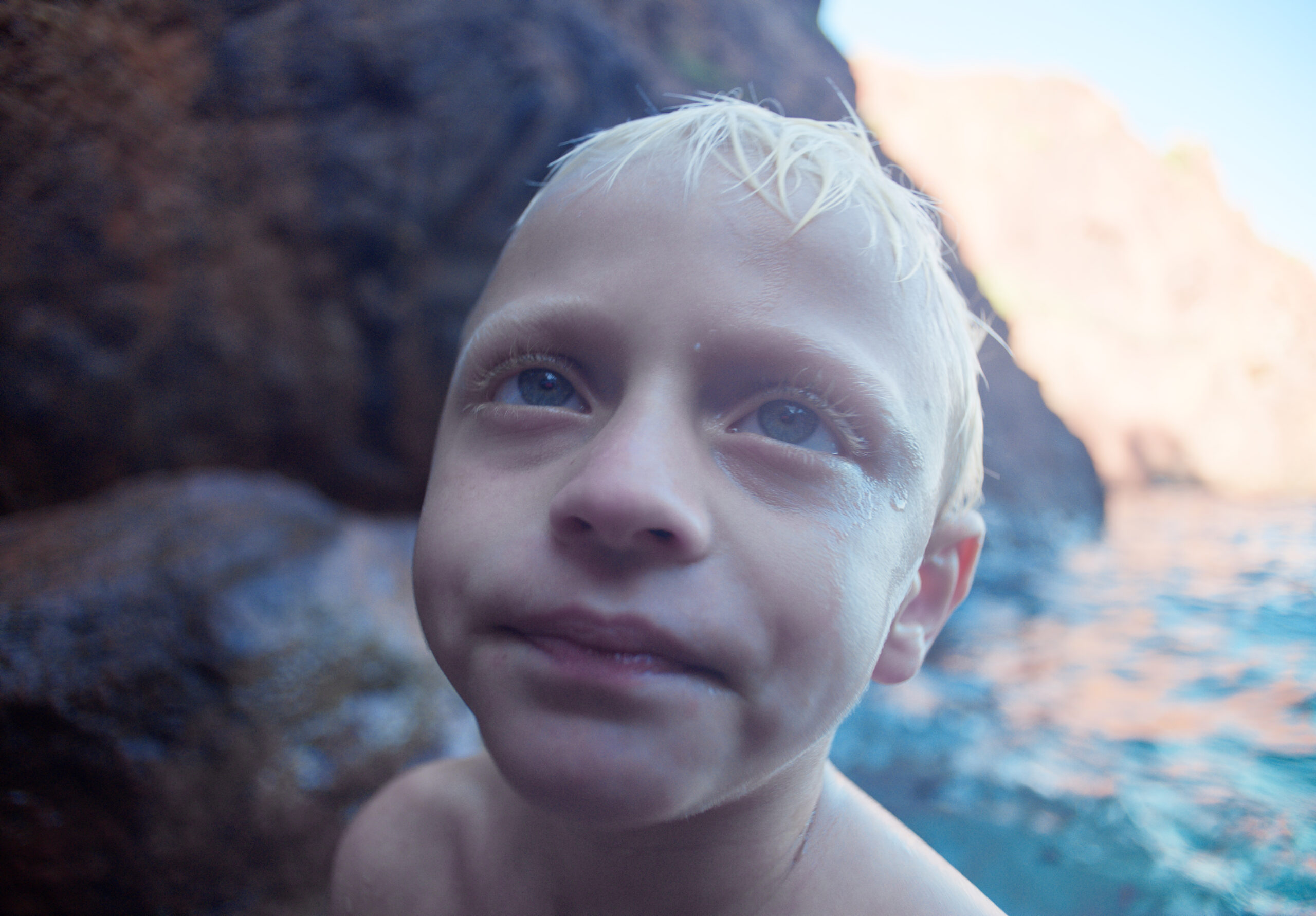 Fotogramma di Red Rocks: primo piano di un bambino biondo, sullo sfondo il mare e le scogliere