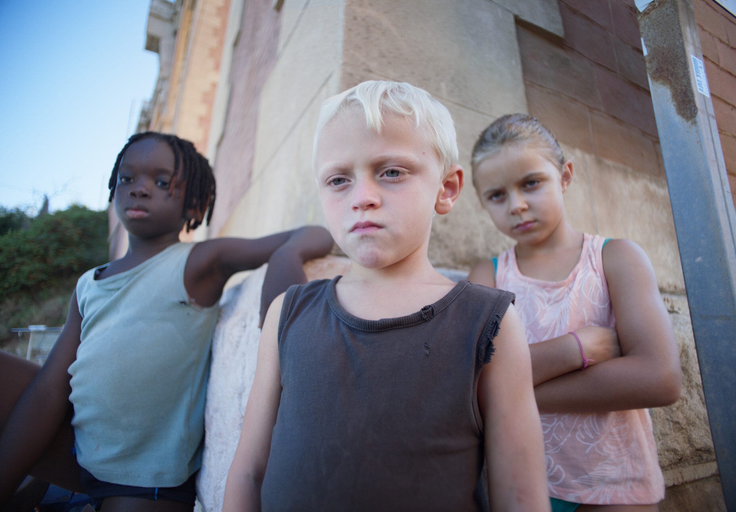 Fotogramma di Red Rocks: tre bambini appoggiati al muro di una casa